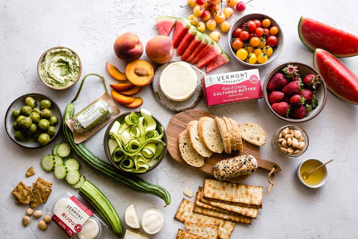 cheese board ingredients arranged prettily on a neutral plaster surface 