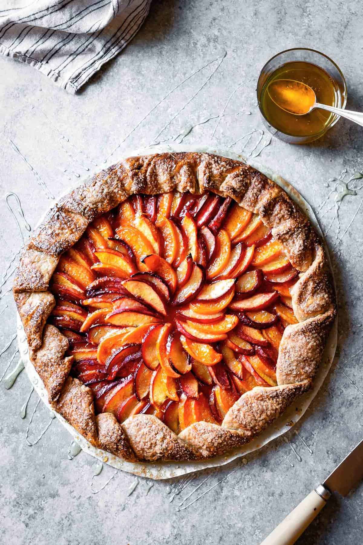 A baked galette with concentric circles of red and orange fruit that looks like a glorious sunflower