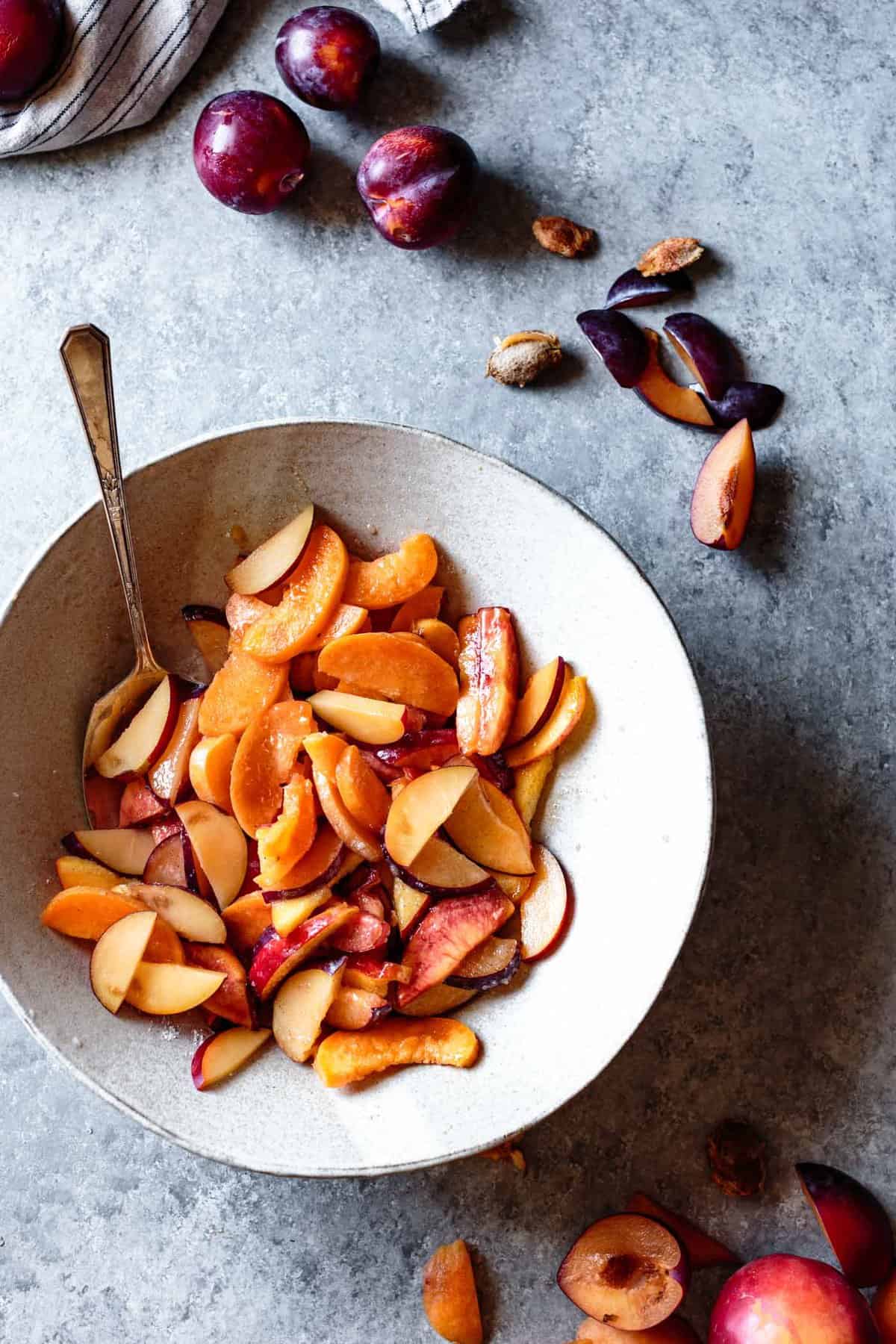 A gray bowl of stone fruit slices, tossed with sugar, cornstarch, and lemon