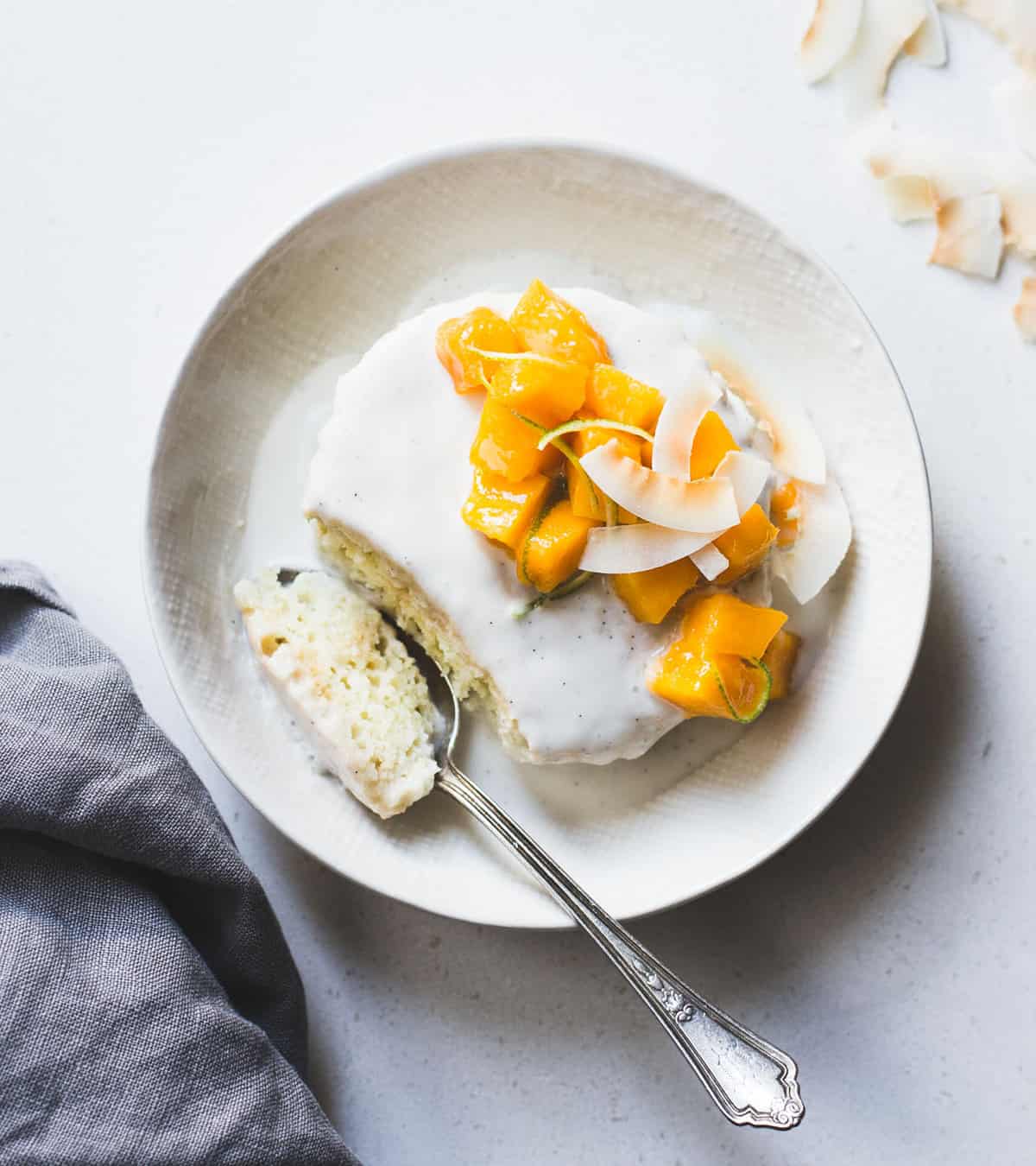 a round coconut tres leches cake topped with mango chunks from my cookbook Alternative Baker