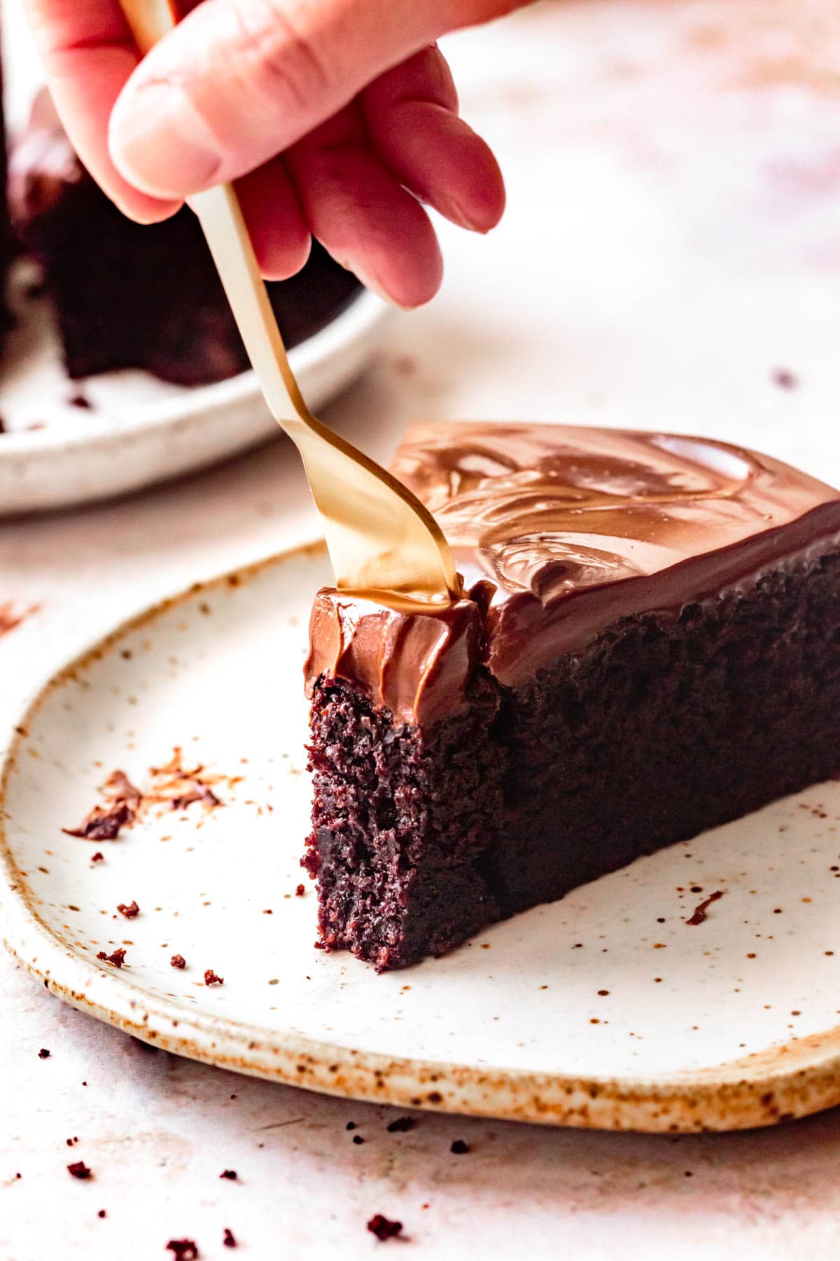 A gold fork dives into a slice of rich, decadent chocolate cake