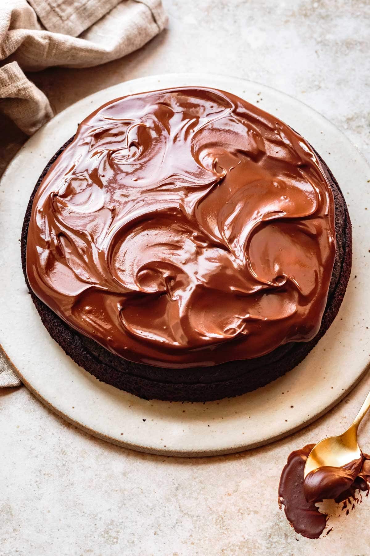 glossy swirls of vegan chocolate ganache sit atop a chocolate cake