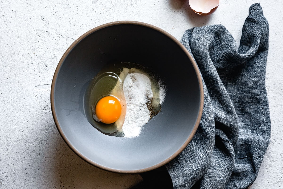 an egg and flour in a bowl for the custard