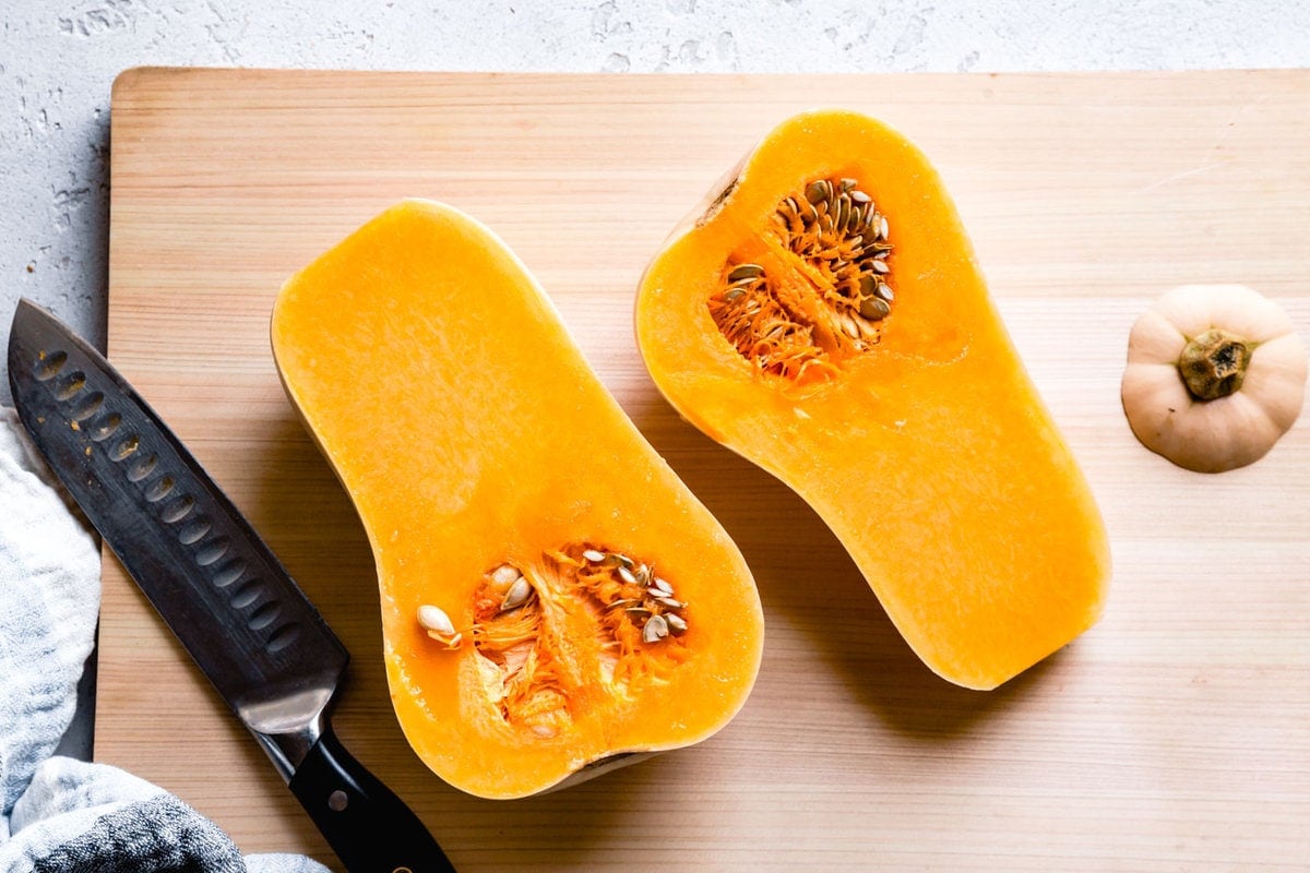 butternut squash cut in half on a cutting board