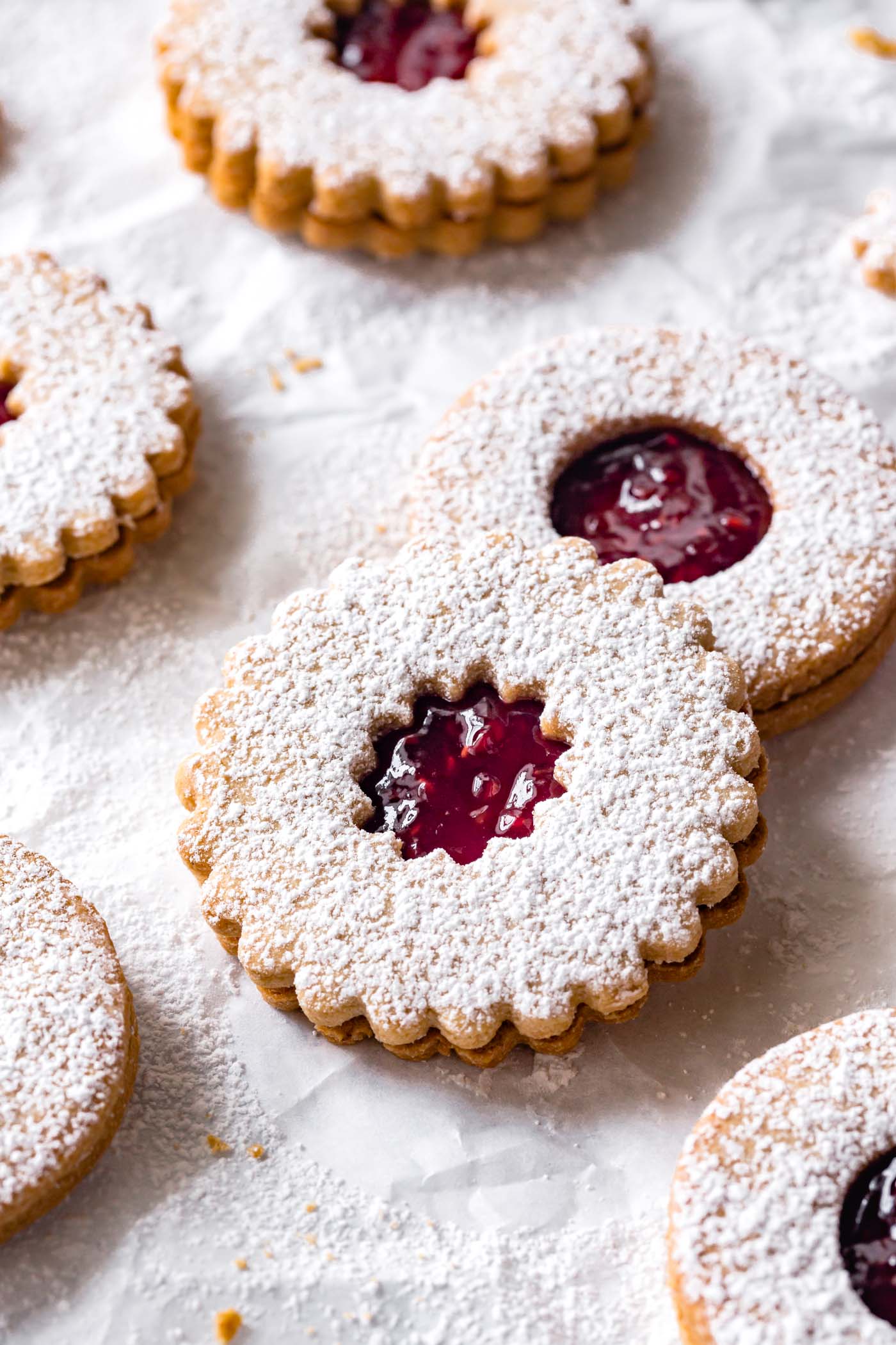 A close-up of two gluten-free linzer cookies, one leaning on the other