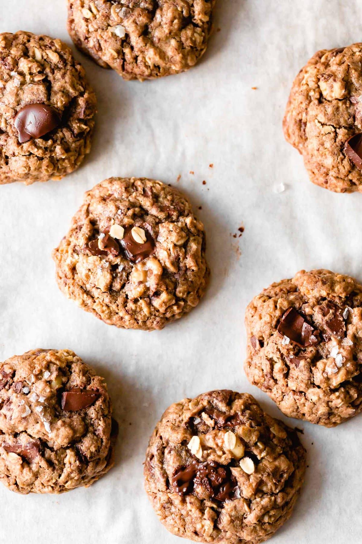 Teff cookies are on a piece of parchment paper topped with glistening melty chocolate chunks