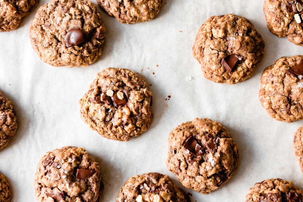 a jumble of freshly-baked teff chocolate chip cookies on a parchment-lined baking sheet