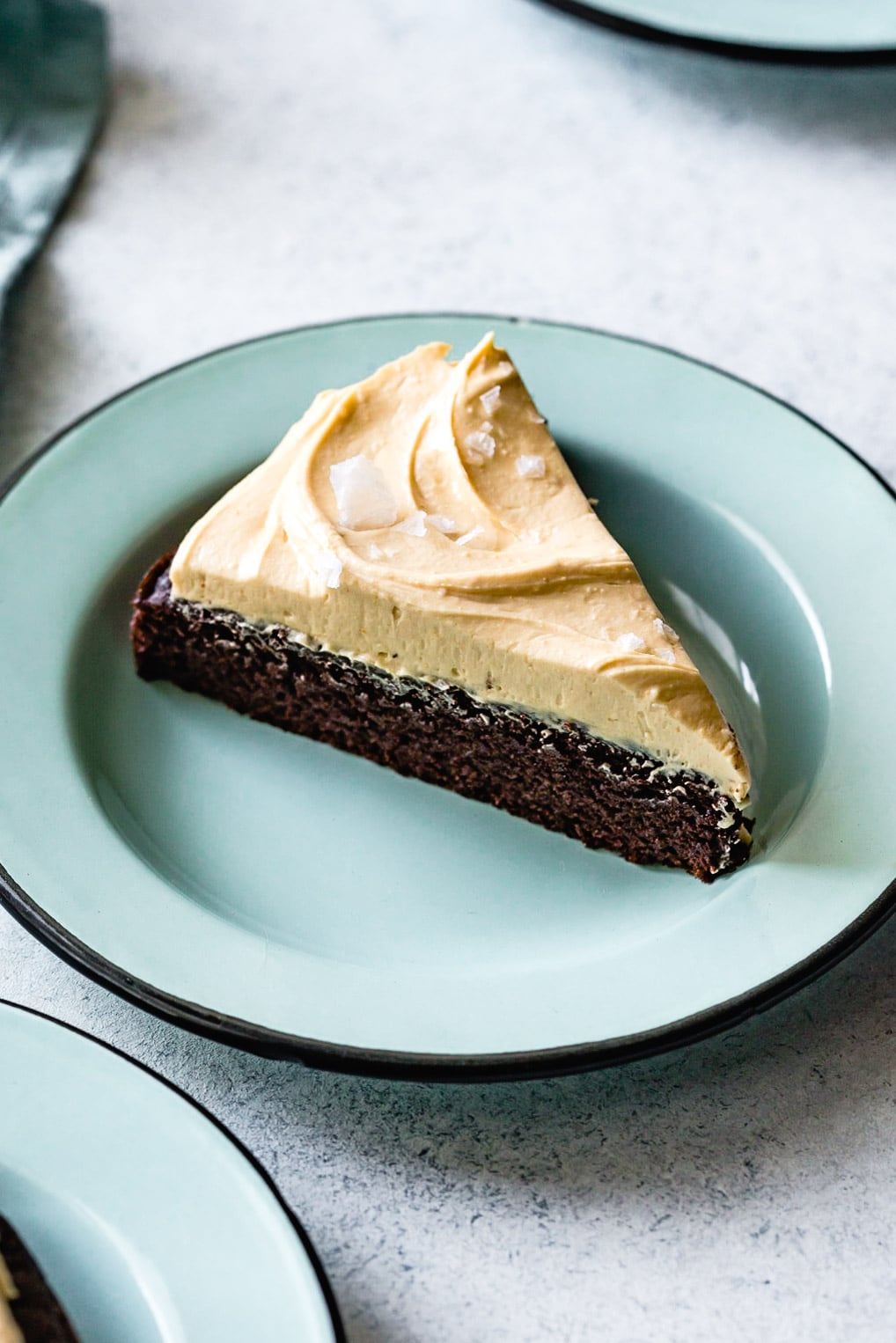 closeup shot of a slice of cake showing layers of fudgy chocolate cake and creamy frosting