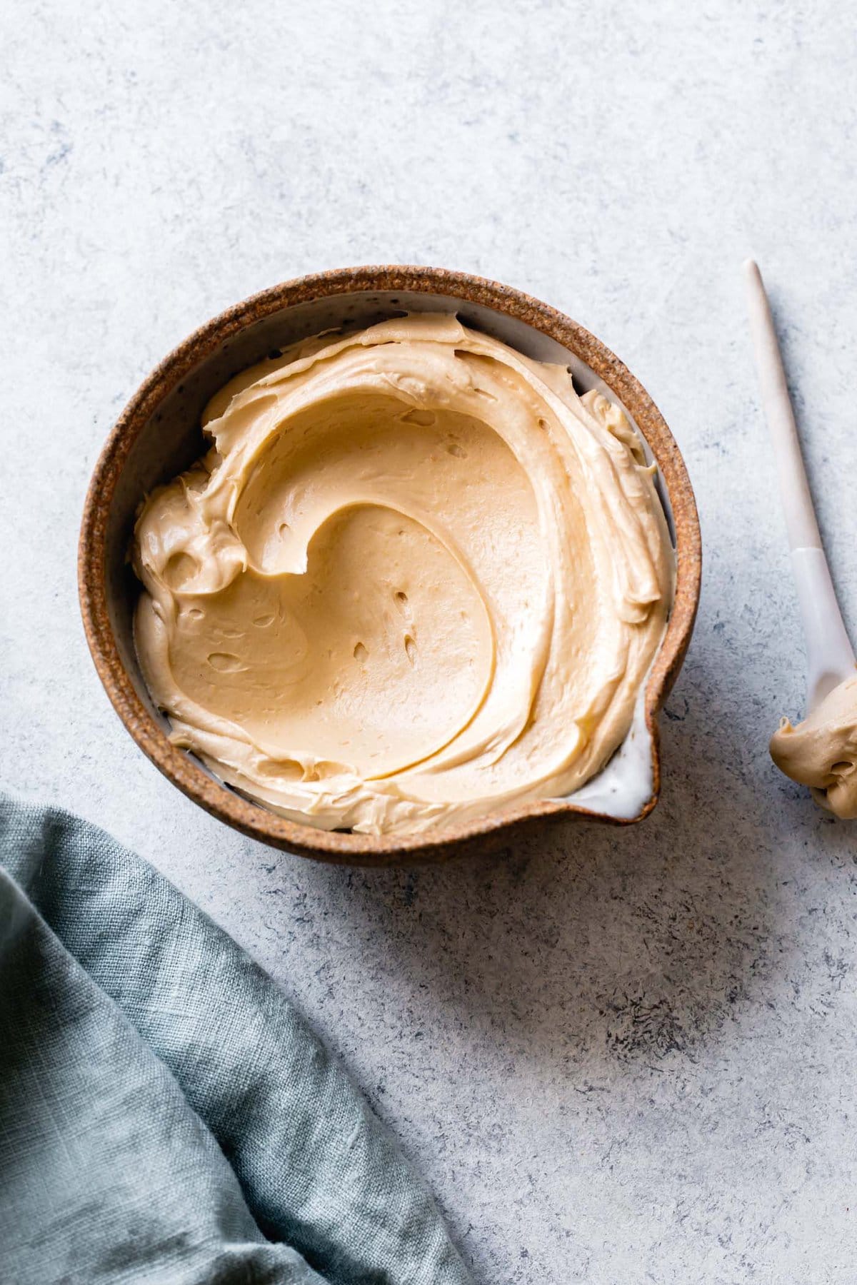 a stoneware bowl has a gorgeous swirl of fluffy peanut butter frosting in it
