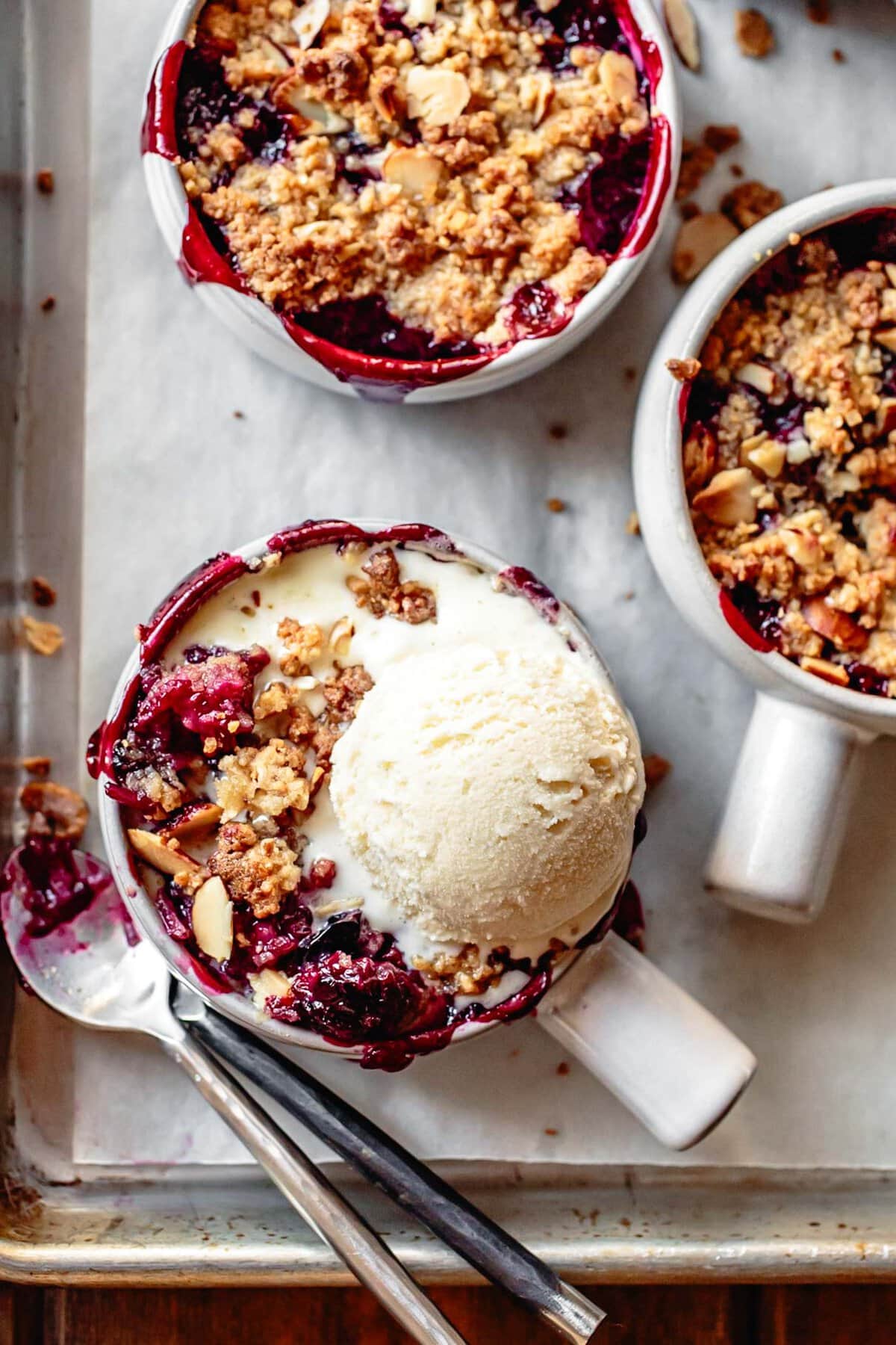 A scoop of ivory cream melts atop red berry crisp
