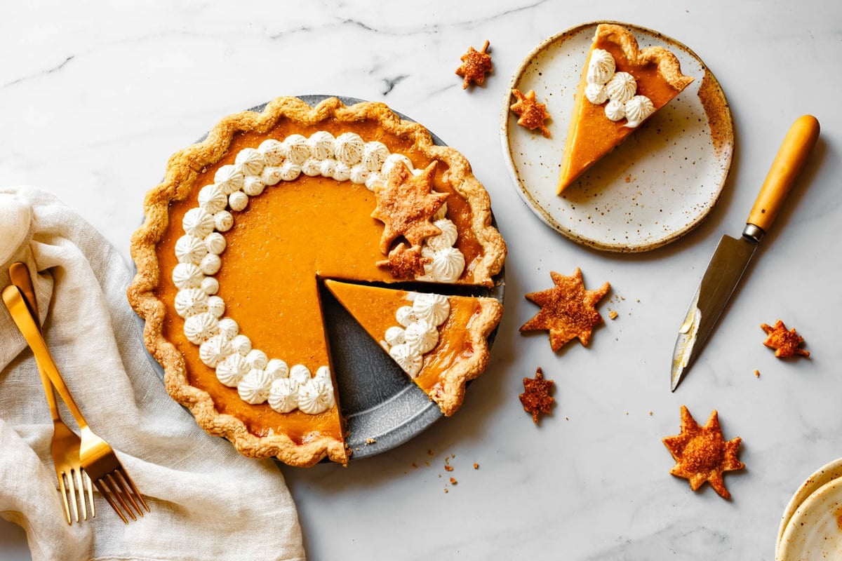 a beautiful orange pumpkin pie has been piped with whipped creme fraiche and is being served up