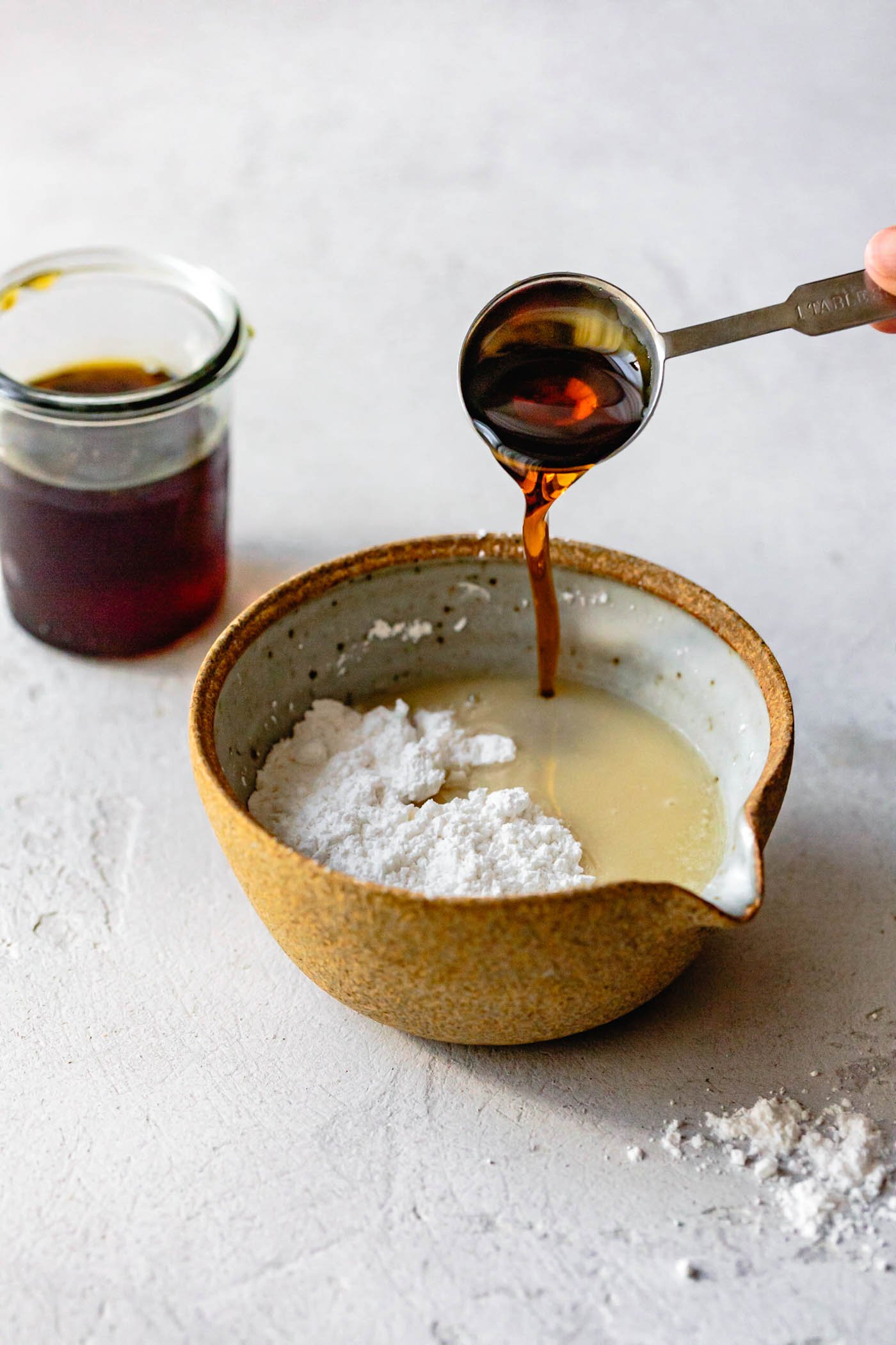 maple syrup is being poured into a bowl with powdered sugar and butter