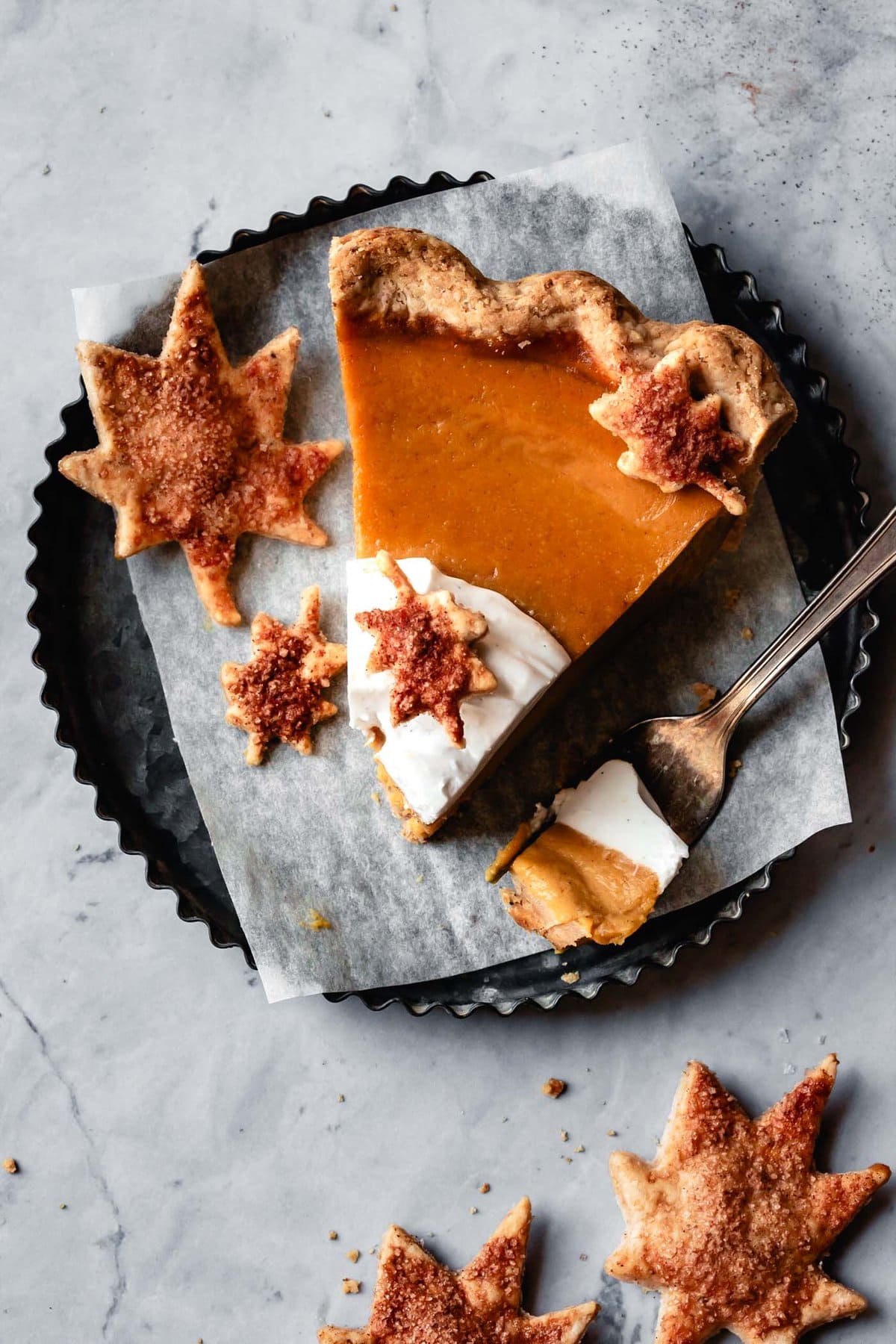 a slice of paleo pumpkin pie is on a small metal plate with a bite taken out