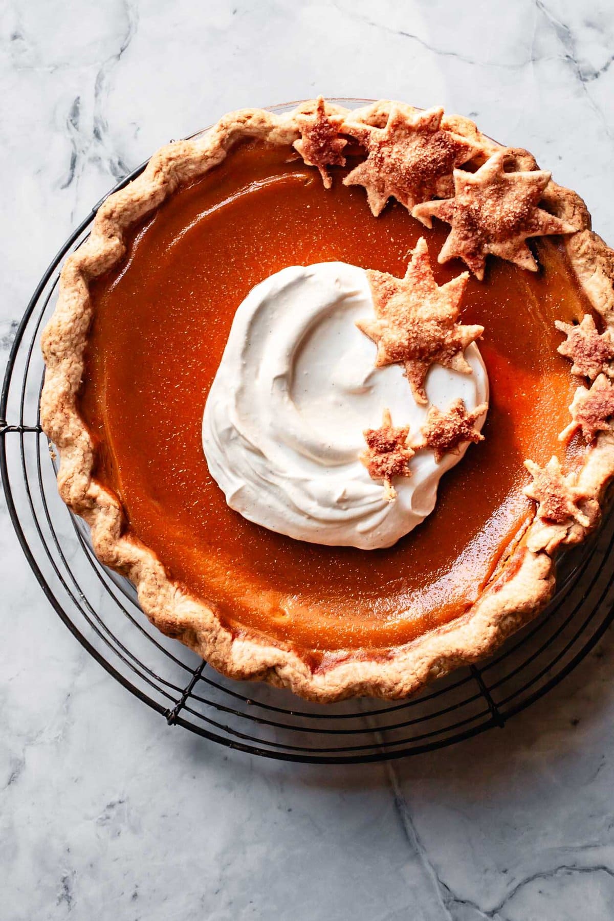 a paleo pumpkin pie has been topped with a swirl of whipped coconut cream and pretty leaf cut-outs made from extra pie crust