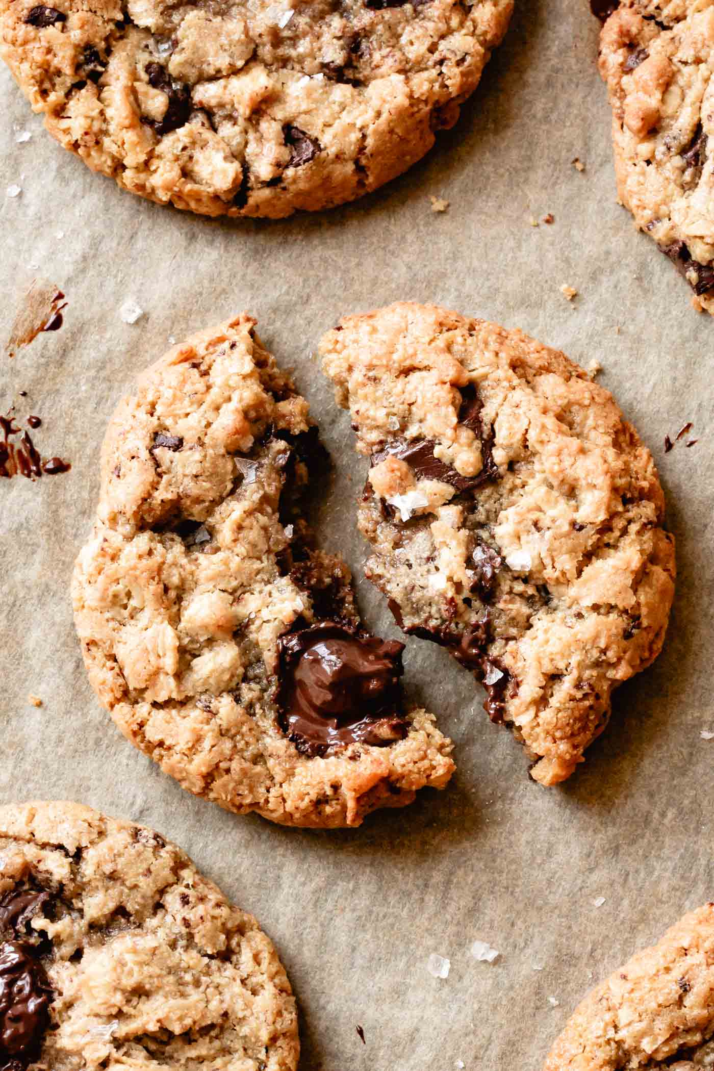 a broken almond flour oatmeal cookie is on a sheet pan looking gooey