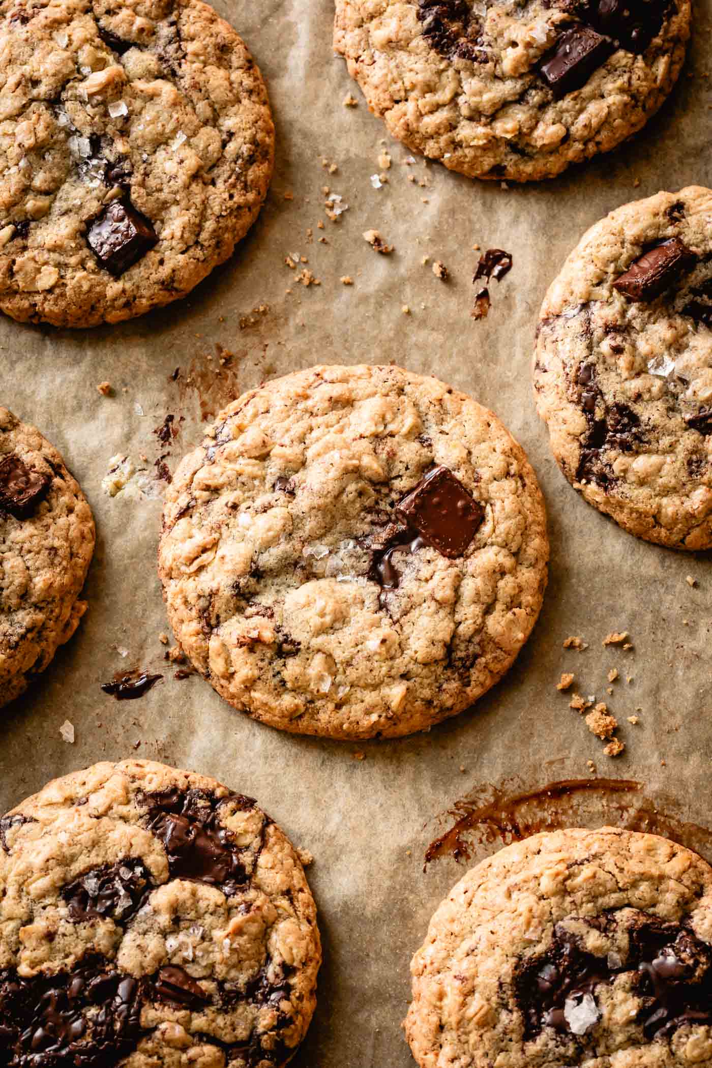 gluten-free chocolate chip cookies are on a messy piece of parchment looking gooey and tantalizing