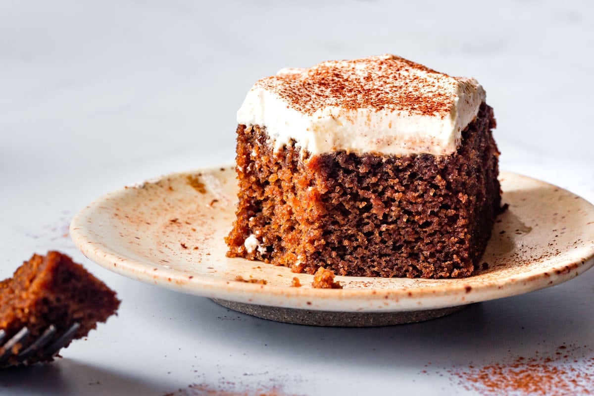 a slice of gluten-free gingerbread cake is on a plate with a bite taken out