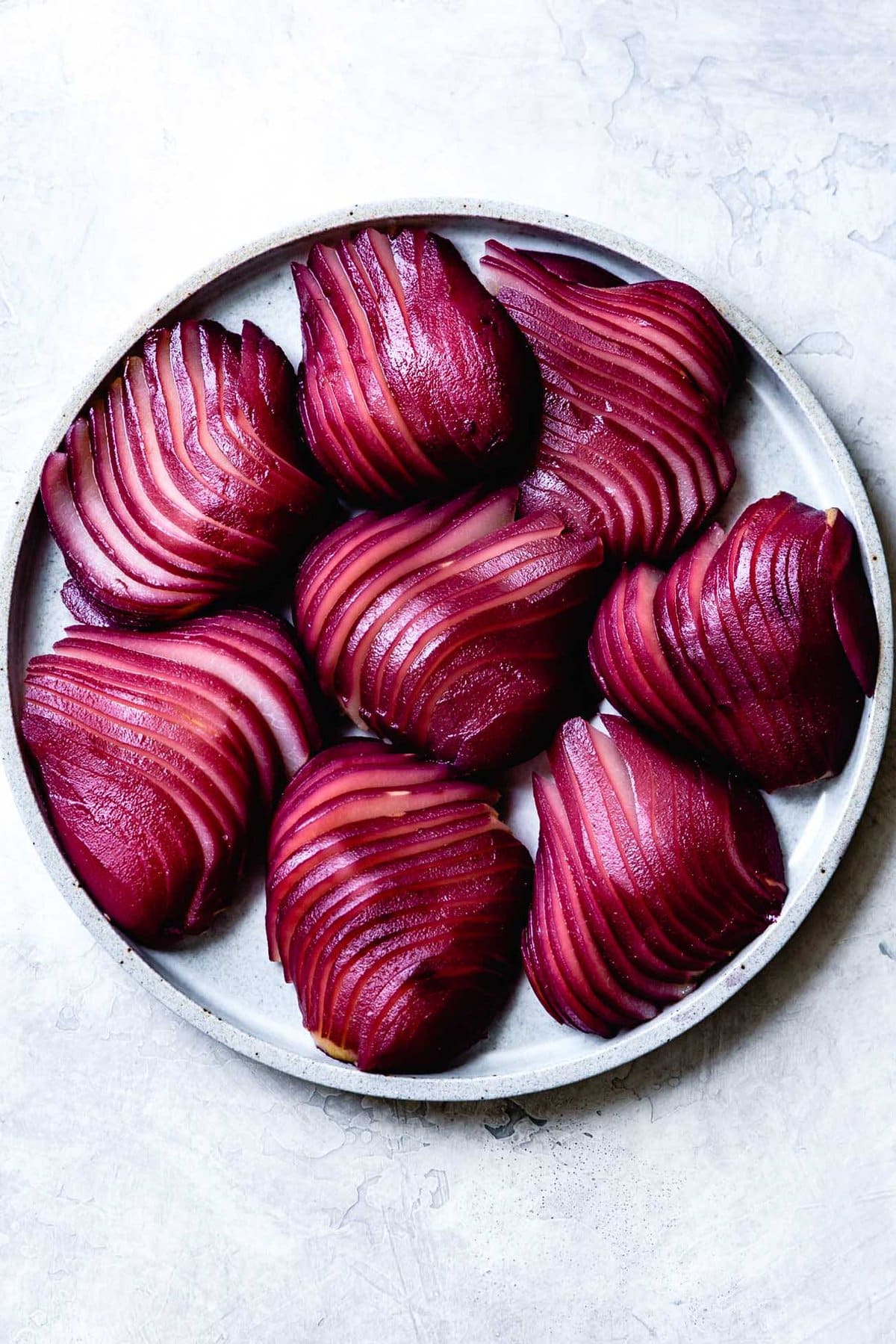a plate of sliced red wine poached pears looks super cool with red and beige stripes