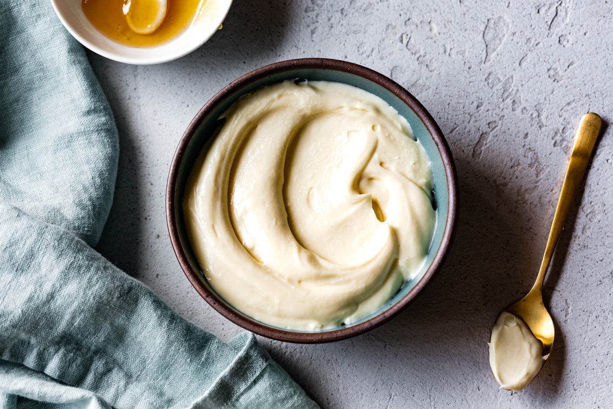 a blue bowl holds a swirl of silky honey frosting 