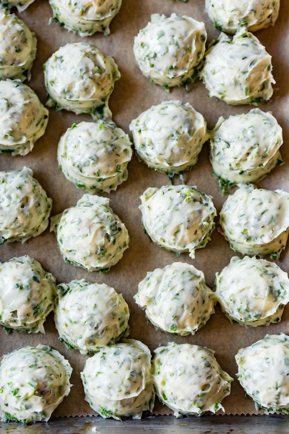 scoops of herb butter are on a lined baking sheet