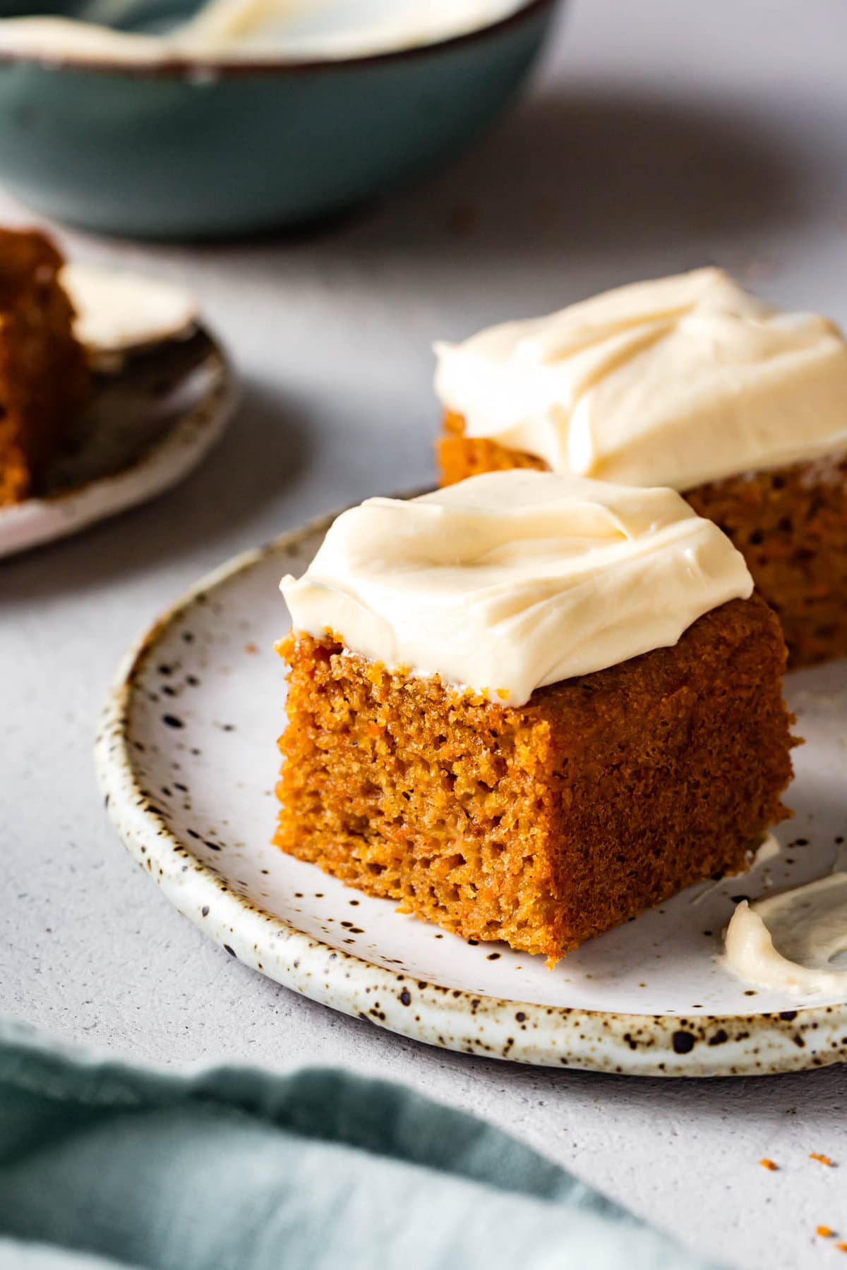 honey cream cheese frosting topped carrot cake slices are on a plate
