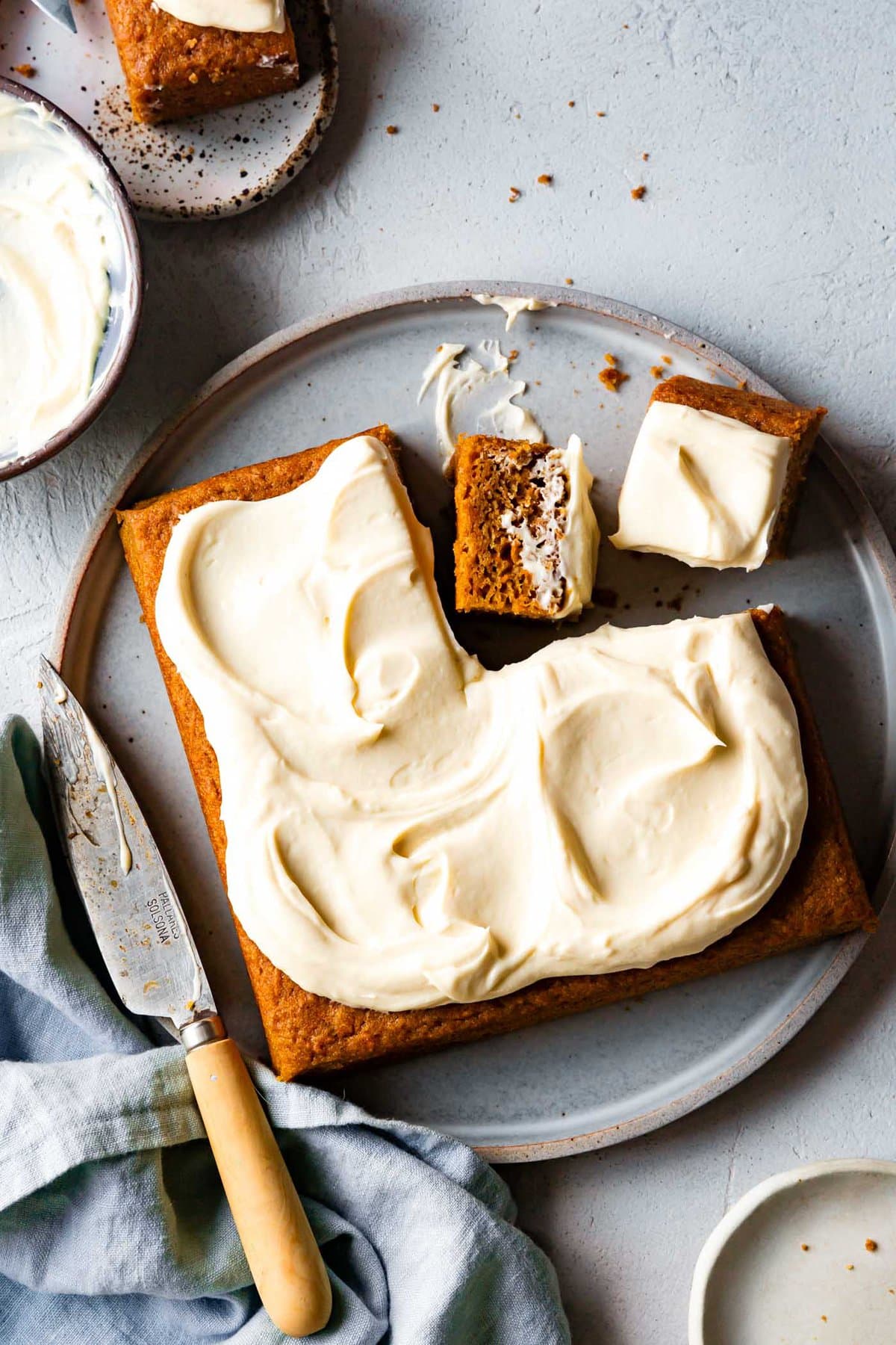 a square paleo carrot cake is on a plate with 2 squares cut out
