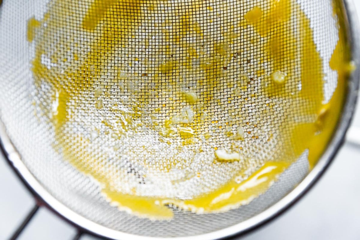 a strainer has caught some eggy bits from the curd