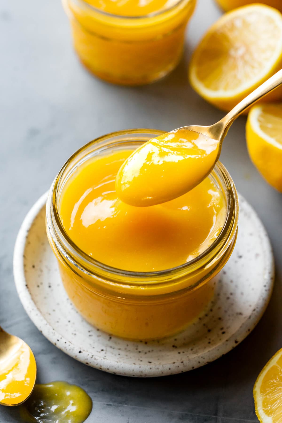a spoon lifts lemon curd out of a jar
