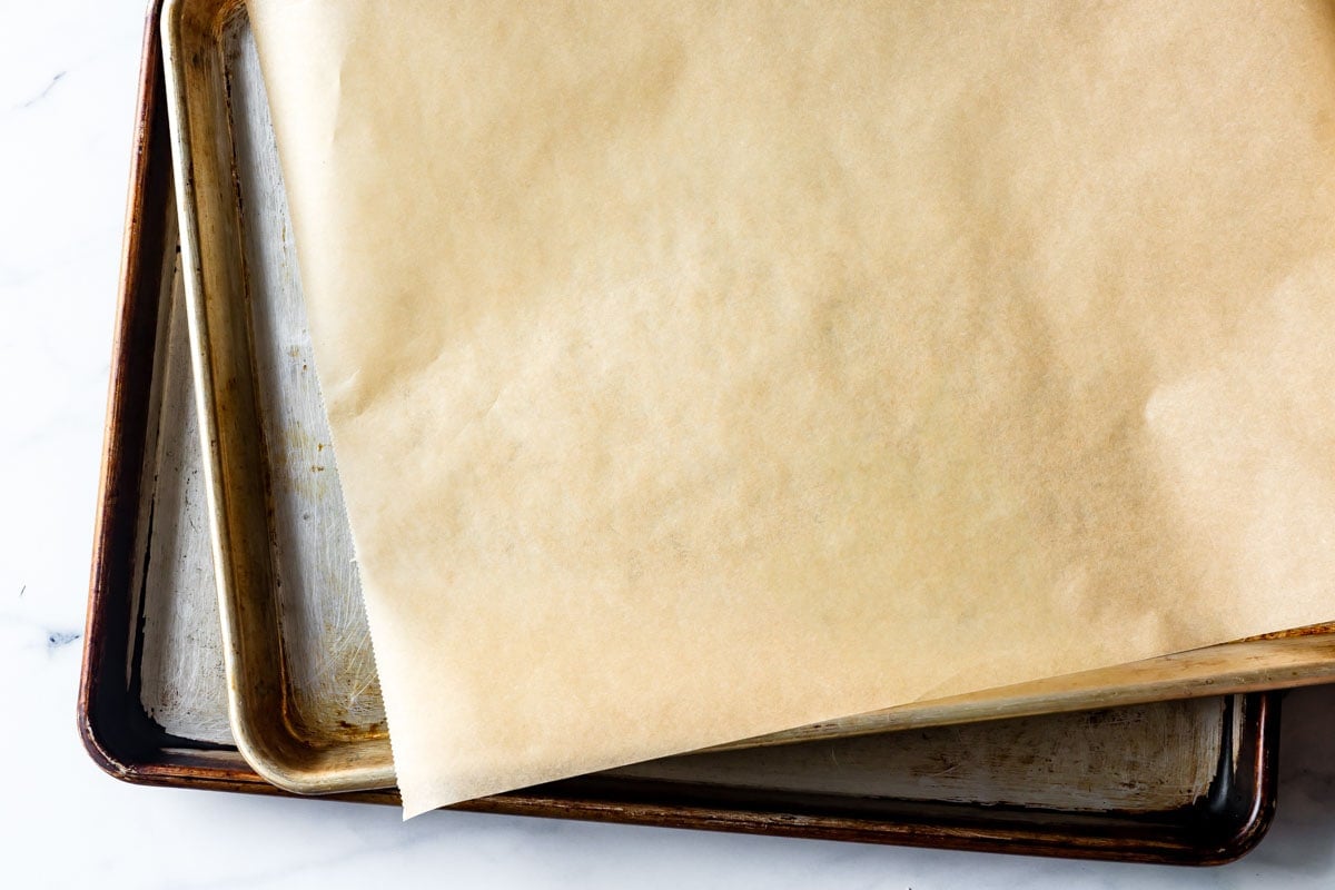two baking sheets are stacked and topped with parchment