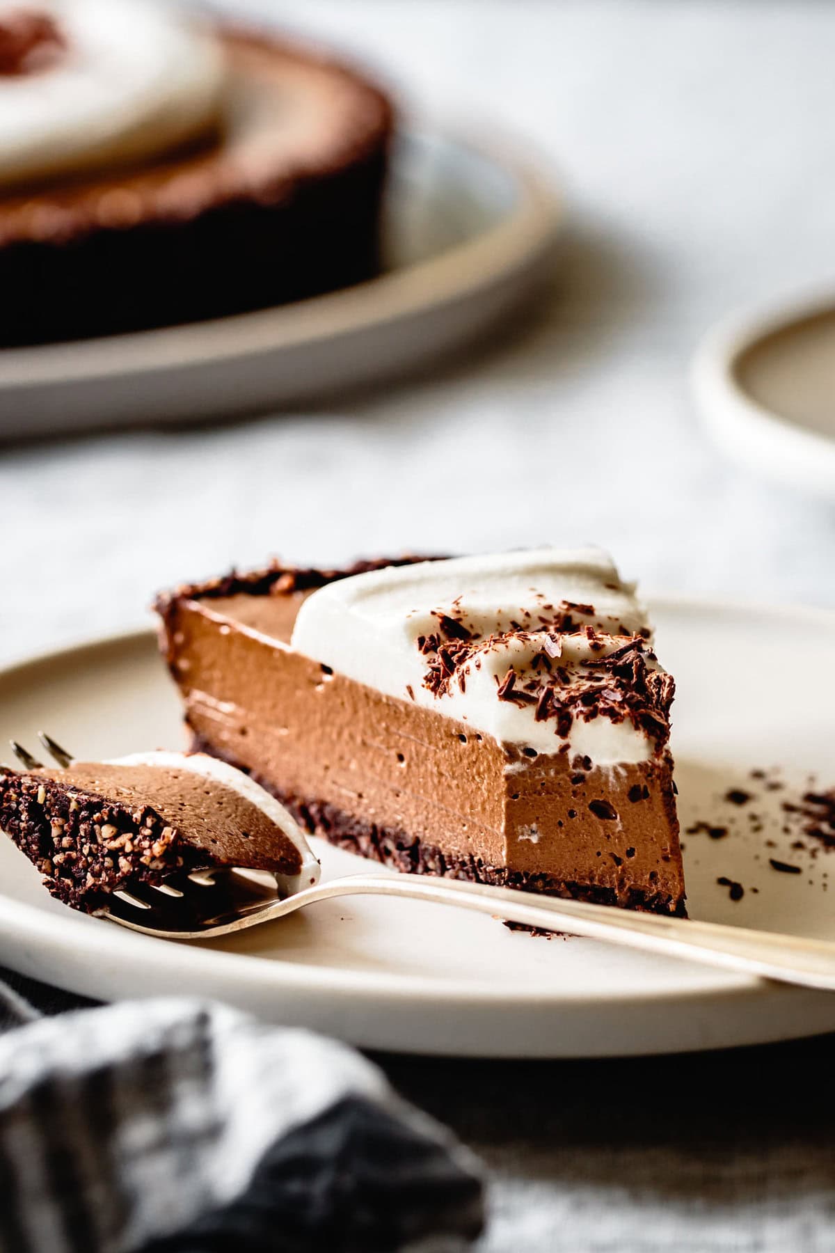 a slice of raw vegan chocolate tart is crowned with luscious coco whip