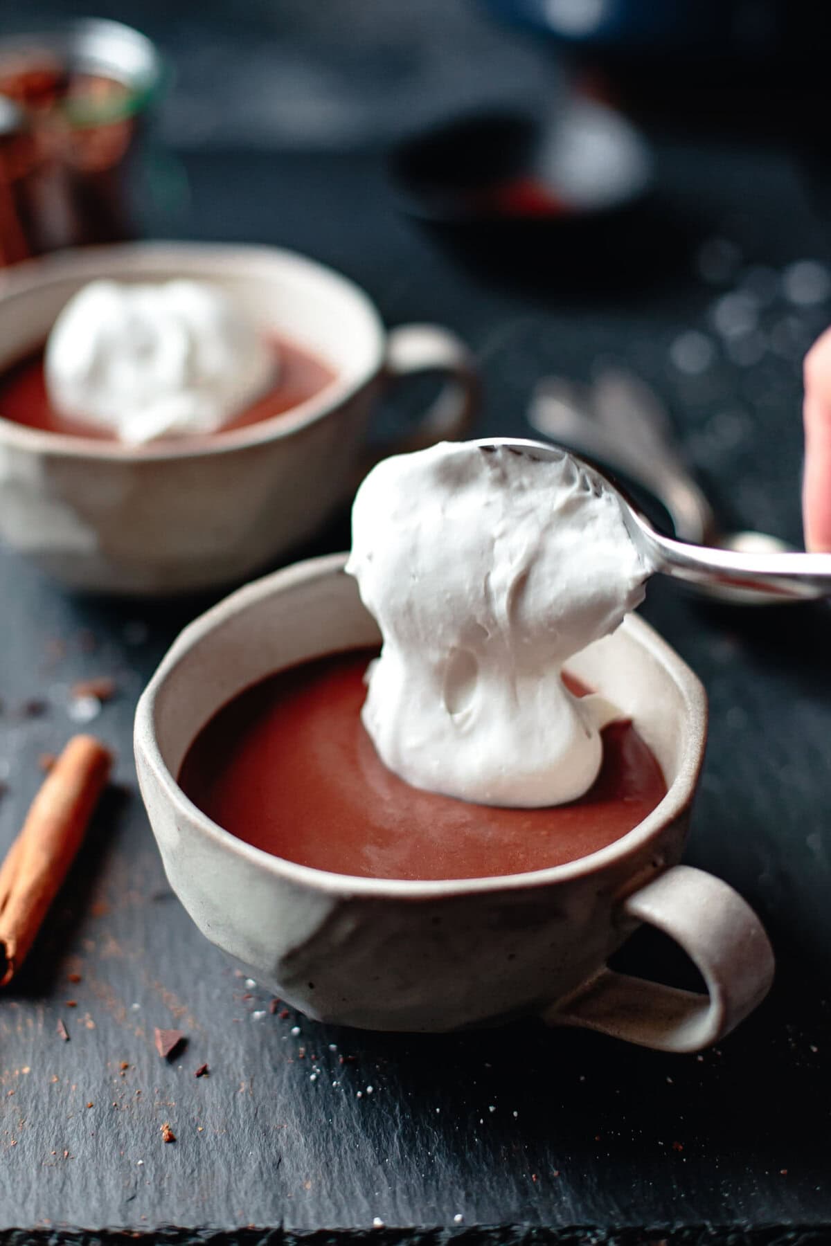 a scoop of fluffy whipped coconut cream gets dolloped over a mug of hot chocolate