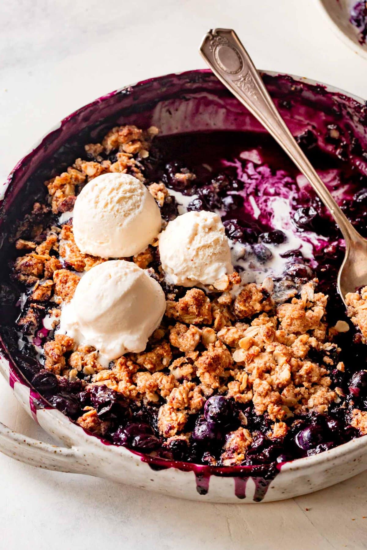 baked crisp is in a baking dish with rivulets of deep purple juice dripping down the side of the pan 
