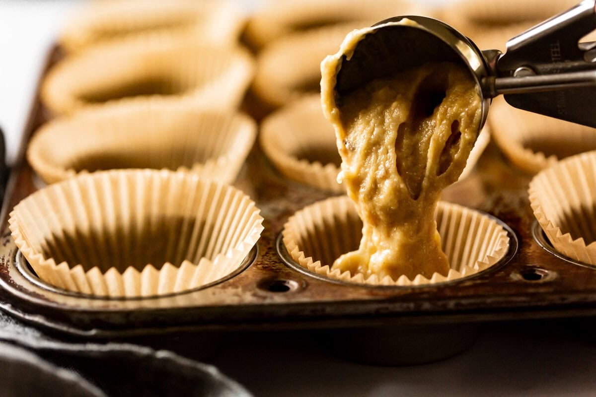 portioning batter into muffin cups lined with paper liners