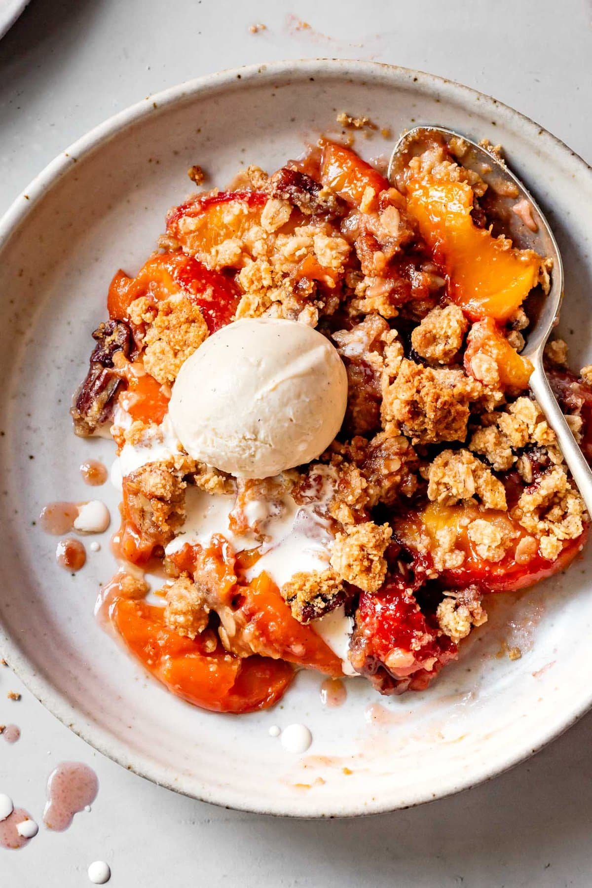 a bowl of juicy peach crisp topped with ice cream